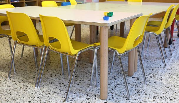 Çocuksuz bir anaokulundaki sarı sandalyeler. - Fotoğraf, Görsel