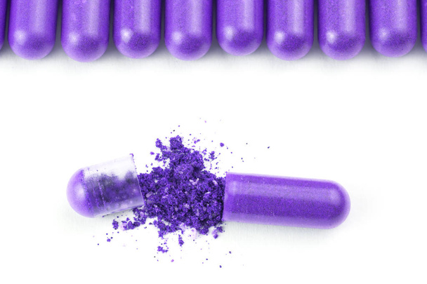 row of proton purple color organic capsules isolated on white background closeup with one opened - Valokuva, kuva