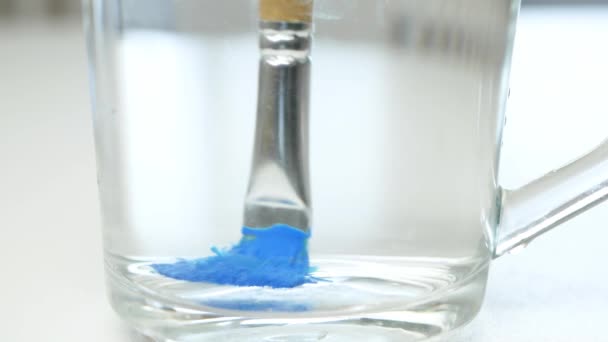 Artist Clean a Used Paint Brush and Spread Blue Color in a Glass with Water - Filmati, video