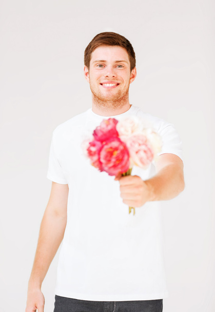 jonge man houden boeket van bloemen - Foto, afbeelding