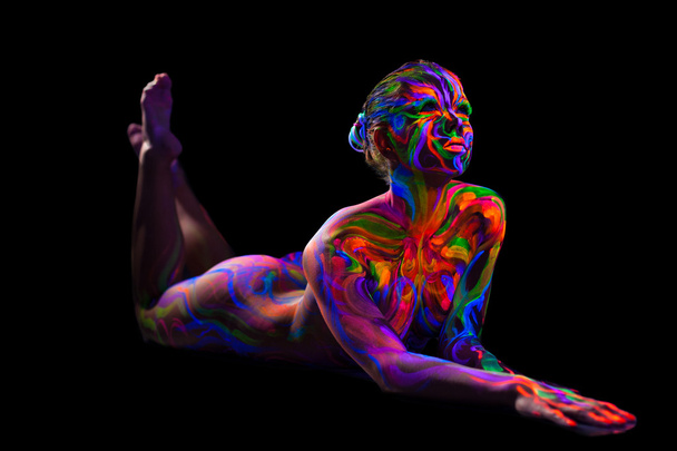 Futuristic girl with neon make-up lying in studio - Фото, изображение
