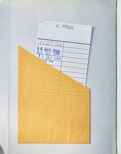 Un libro abierto mostrando cubierta texturizada con una tarjeta Check Out
. - Foto, Imagen