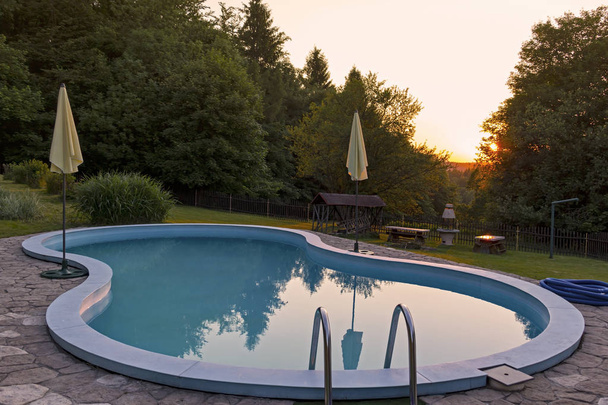 Swimmingpool im Garten und ein schöner Sonnenuntergang - Foto, Bild