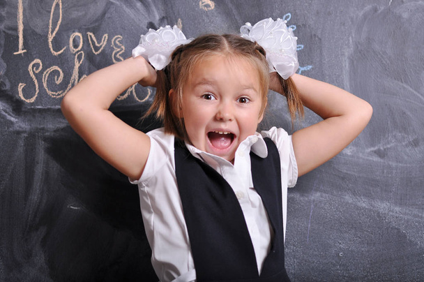 Porträt einer schönen lächelnden jungen Erstklässlerin auf Tafel-Hintergrund. Schul- und Bildungskonzept - Foto, Bild