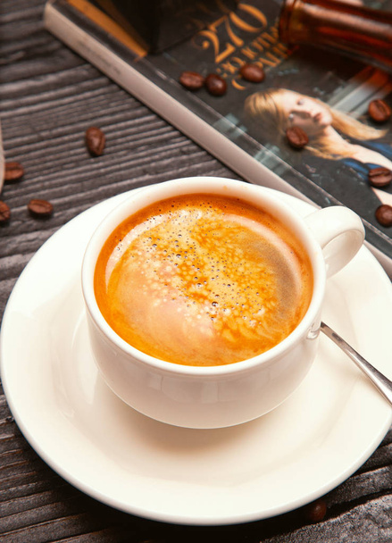 Cappuchino leitoso espuma em copo branco decorado com grãos de café e revistas
.  - Foto, Imagem