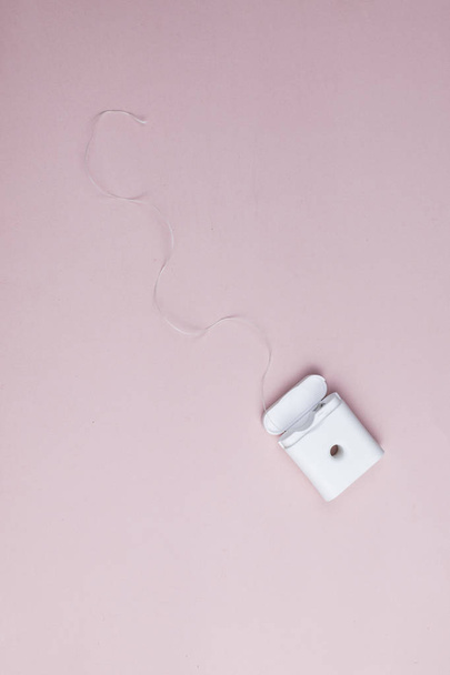 Dental floss in a plastic box on a pink background - Fotó, kép