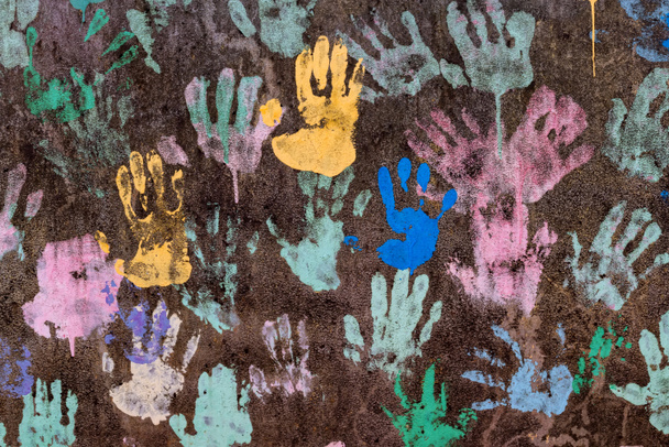 Fondo oscuro con coloridas huellas de manos que simbolizan la amistad interracial
 - Foto, imagen