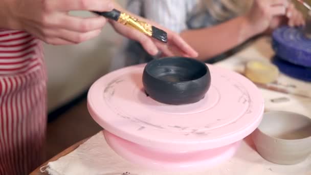 Γυναίκα καλύπτει με μαύρη βαφή ένα κεραμικό κύπελλο στο εργαστήριο - Πλάνα, βίντεο