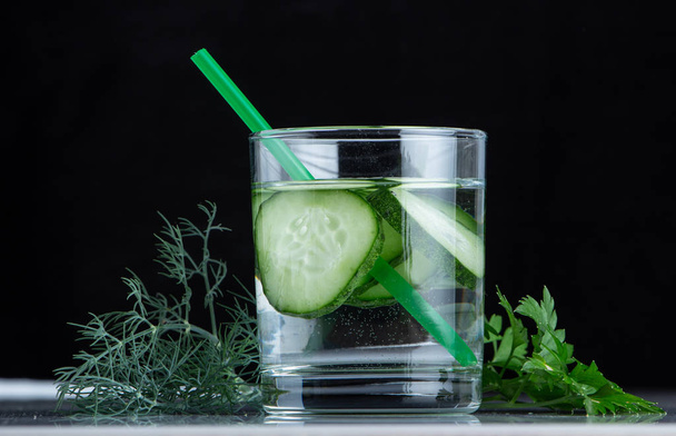 Cucumber water, cleansing water to detoxify the body and quench thirst on a black background. - Foto, immagini