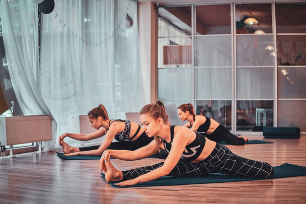 Mädchen machen gemeinsam Übungen bei Yoga-Kurs - Foto, Bild