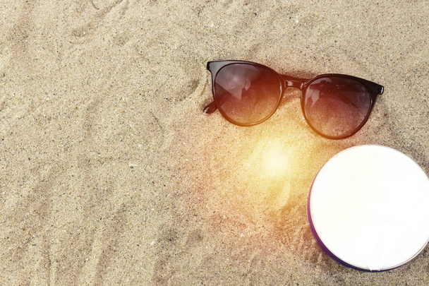 Sunglasses and cream on sand, summer concept - Photo, Image