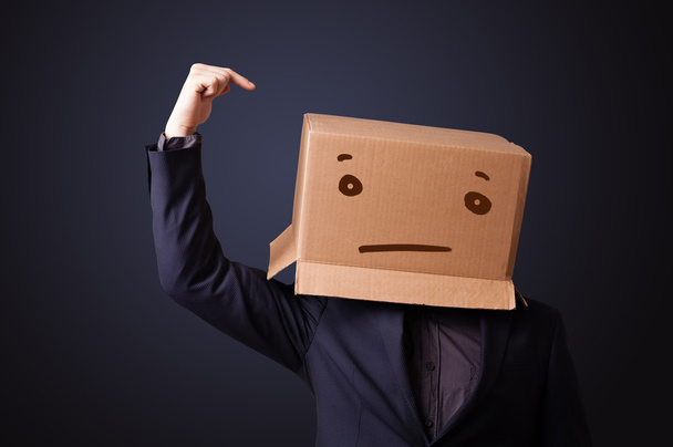 Young man gesturing with a cardboard box on his head with straig - Foto, Imagem