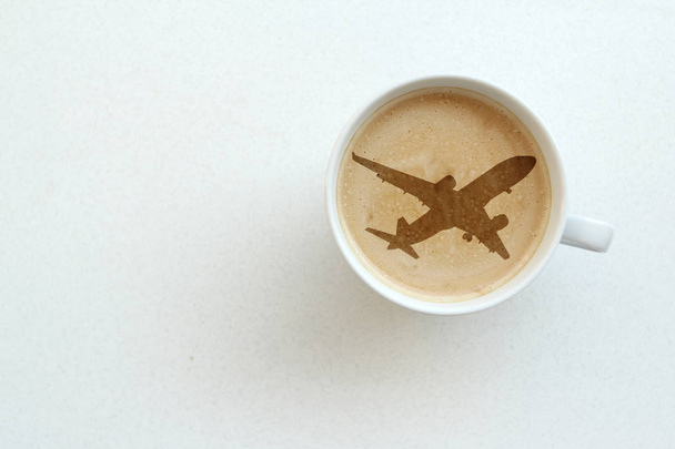 white wide cup of coffee, cappuccino with milk, cocoa with an airplane pattern on a white table, top view, save space, close-up, concept of travel, transfer - Fotografie, Obrázek