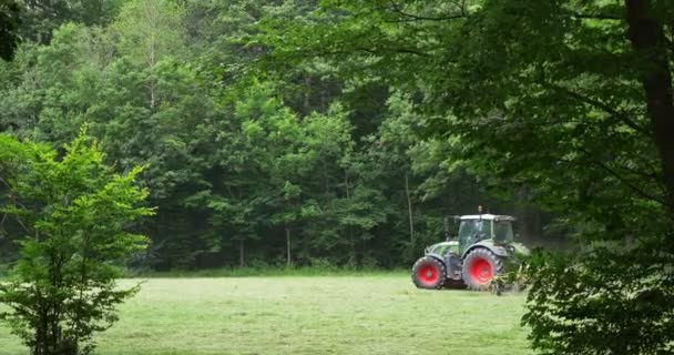 Yeşil ormanın arka planı üzerinde tarlada çalışan traktör - Video, Çekim