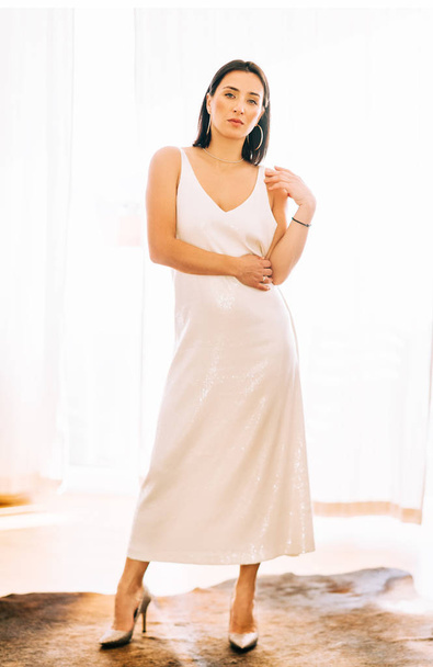 Retrato romántico de una hermosa mujer joven con cabello negro con vestido de lentejuelas blancas
 - Foto, imagen
