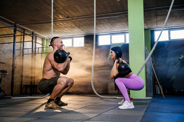 Jeune couple attrayant en tenue de sport faisant de l'exercice dans la salle de gym
. - Photo, image