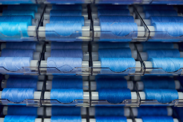Sewing thread reels in blue on the stand in the shop,selective focus,background texture - Photo, Image