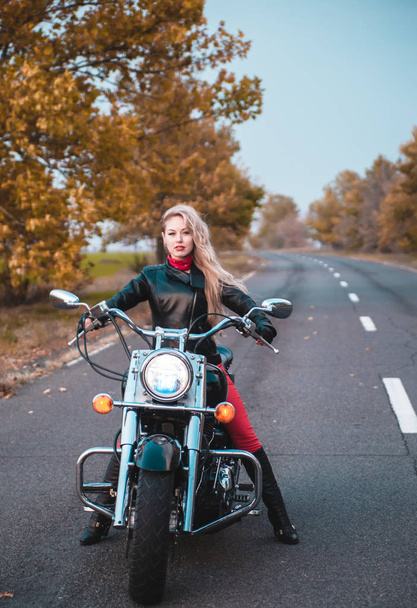 Mulher motociclista elegante com motocicleta na estrada
. - Foto, Imagem
