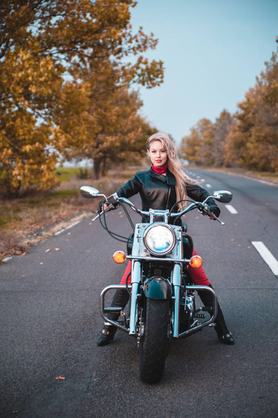 Stijlvolle biker vrouw met motorfiets op de weg. - Foto, afbeelding