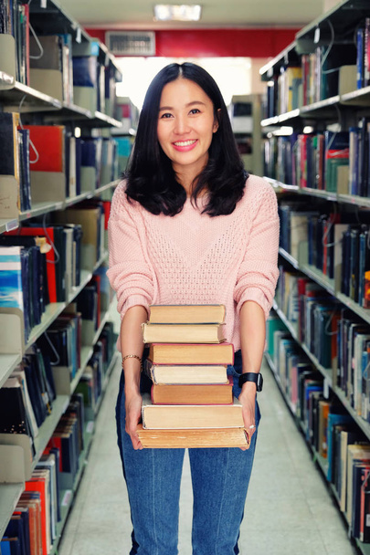 Молода жінка носить важкі книги в бібліотеці
 - Фото, зображення