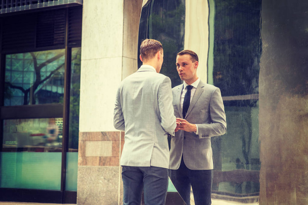 Молодий бізнесмен Модіон у Нью-Йорку. Молодий чоловік у сірому піджаку, біла сорочка, чорна краватка, чорні штани, стоїть на вулиці перед металевим дзеркалом, дивиться на відображення, думає - Фото, зображення