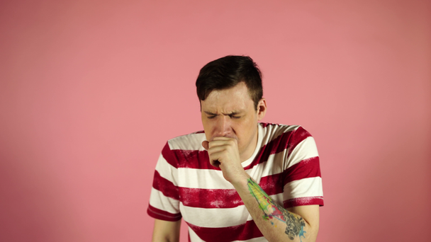 Mann hustet stehend auf rosa Hintergrund. sich unwohl oder krank fühlen - Filmmaterial, Video