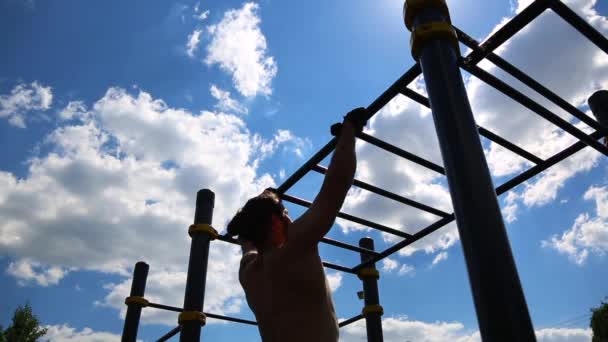 Концепция спортивной мотивации. Вид сзади на мускулистого человека, стоящего на горизонтальном перекладине на открытом воздухе в солнечный день. Тренировки на свежем воздухе, кроссфит
. - Кадры, видео