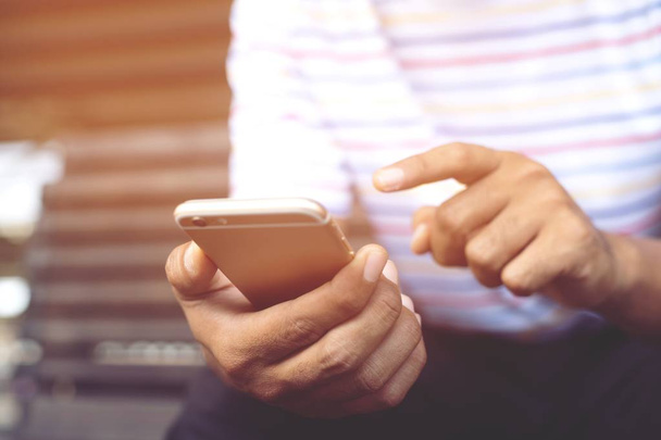 Молодой человек, пользующийся мобильным телефоном во время отдыха в офисе. стоять в ожидании сообщения на мобильном телефоне во время перерыва
. - Фото, изображение