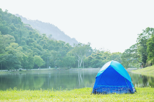 Campeggio tenda blu nella foresta vicino al fiume lago in atmosfera mattina rinfrescante. concetto di viaggio
. - Foto, immagini