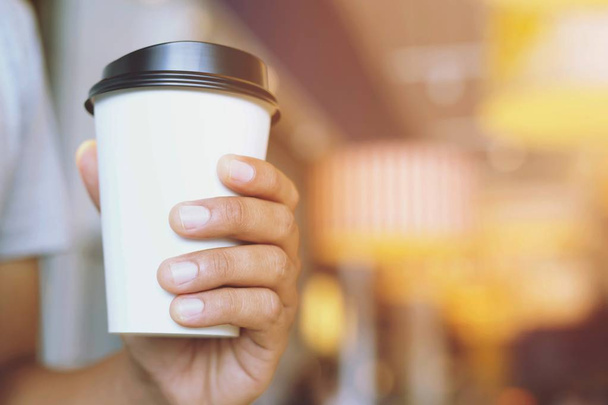 junger Mann hält Pappbecher zum Mitnehmen in der Hand und trinkt Kaffee heiß auf Café-Café. - Foto, Bild