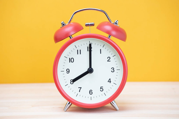 reloj despertador retro vintage de ocho minutos a doce horas en madera de mesa con fondo amarillo
. - Foto, imagen
