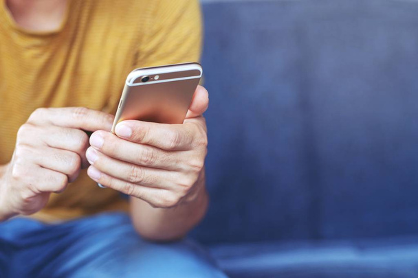 Jeune homme casual porter en utilisant le téléphone portable pendant le repos sur le canapé. assis en regardant le message sur le téléphone mobile pendant la pause se détendre
. - Photo, image