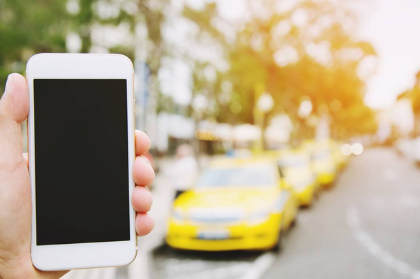 οι άνθρωποι του χεριού δείχνουν λευκό κινητό έξυπνο τηλέφωνο με κενή κενή οθόνη. χώρος για κείμενο ή εφαρμογή Λαμβάνοντας μια κλήση την έννοια του αυτοκινήτου. πάρκινγκ αυτοκινήτων στη σειρά στην πλευρά του δρόμου φόντο - Φωτογραφία, εικόνα