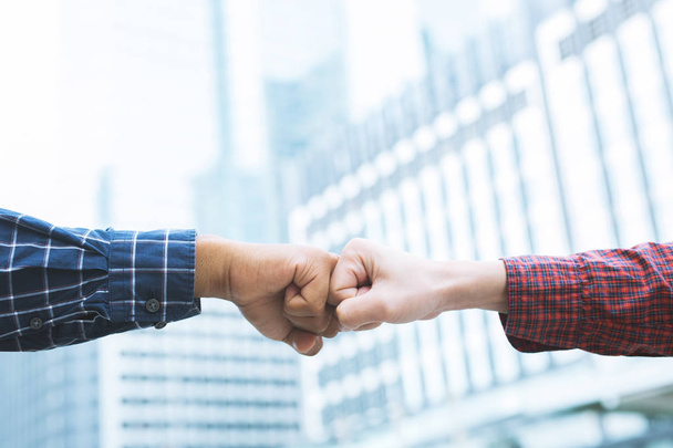 close up image of a fist bump collide agreement. Hands of business man show strength teamwork, handshake negotiations finish together after good deal. Business success concept. building background - Photo, Image