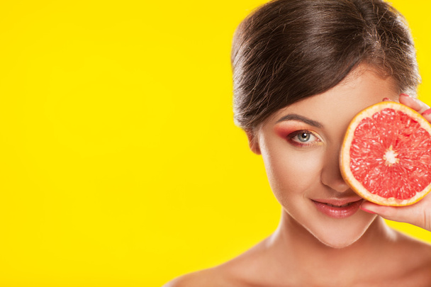 Beautiful young woman with bright make-up, holding grapefruit, o - Photo, Image