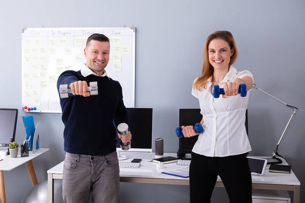 Close-up Of Male And Female Businesspeople Exercising In Office With Dumbbells - Photo, Image