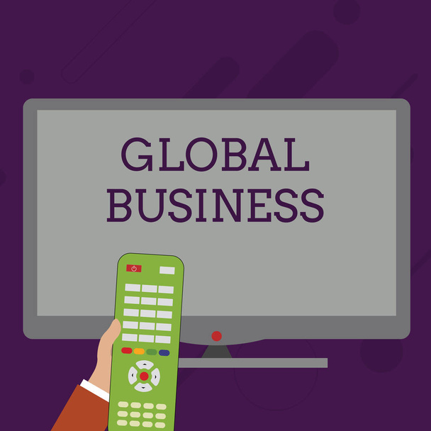 Word writing text Global Business. Business concept for Trade and business system a company doing across the world Hand Holding Computer Remote Control infront of Blank Wide Color PC Screen. - Photo, Image