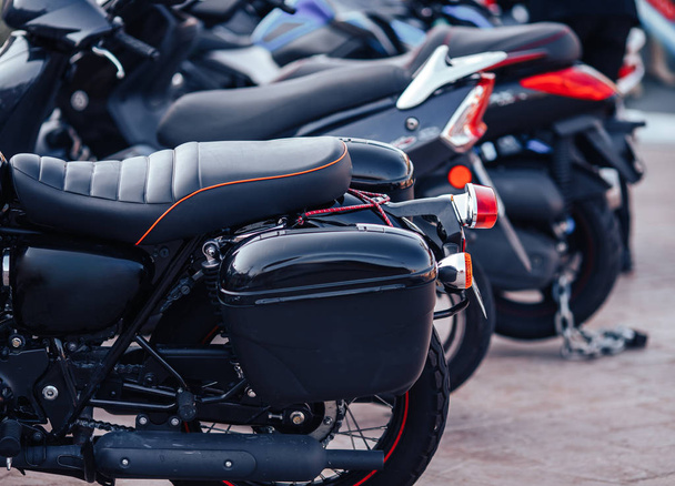 Rent row black scooter motorbikes standing in parking lot - Foto, afbeelding