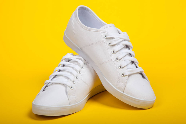 Nowe białe obuwie sportowe na żółtym tle - Zdjęcie, obraz
