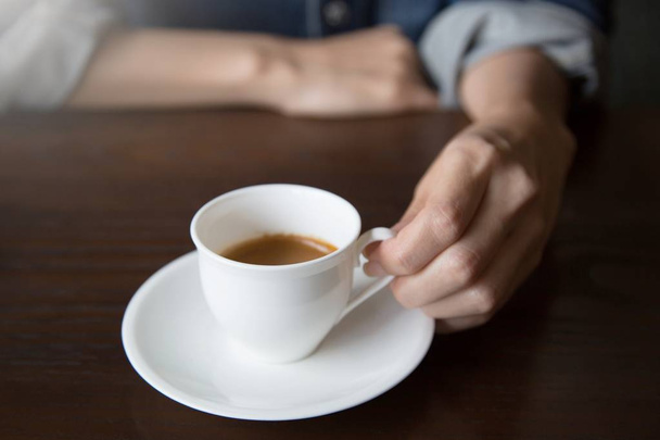 Un giovane in giacca di denim Sorseggiando una bevanda al caffè calda sul tavolo di legno Concept
. - Foto, immagini