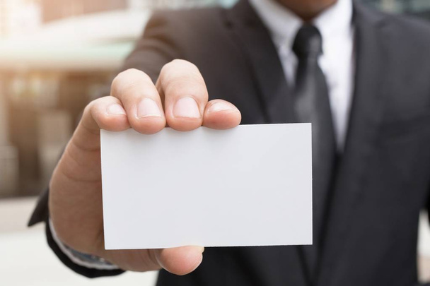 Geschäftsmann in der Hand hält eine weiße Karte mit abgerundeten Ecken. Einfache Call-Card-Attrappe Vorlage halten Arm. Plastik-Kreditkartendisplay vorne. - Foto, Bild