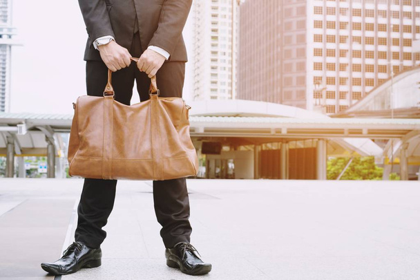 Closeup of a young businessman entrepreneur with boots and a briefcase stand office front - Foto, Bild
