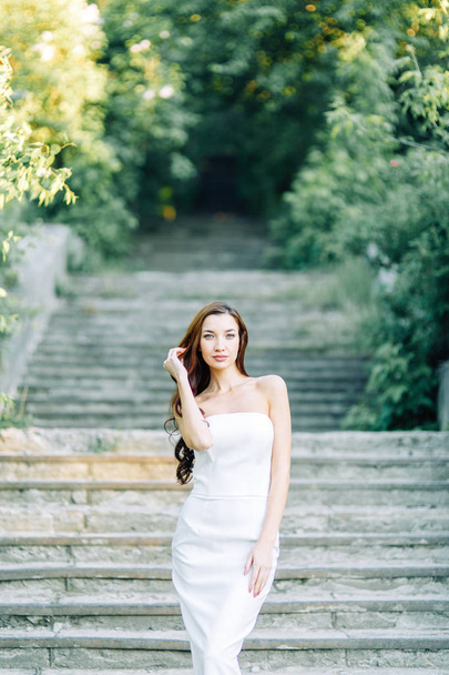Summer photo shoot in the Park at the rocks and stones. Beautiful girl in white dress and hat.  - Foto, imagen