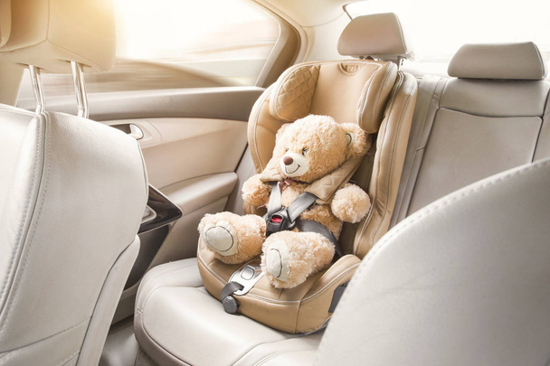 Seggiolino auto di sicurezza per bambino con orsacchiotto beige
 - Foto, immagini