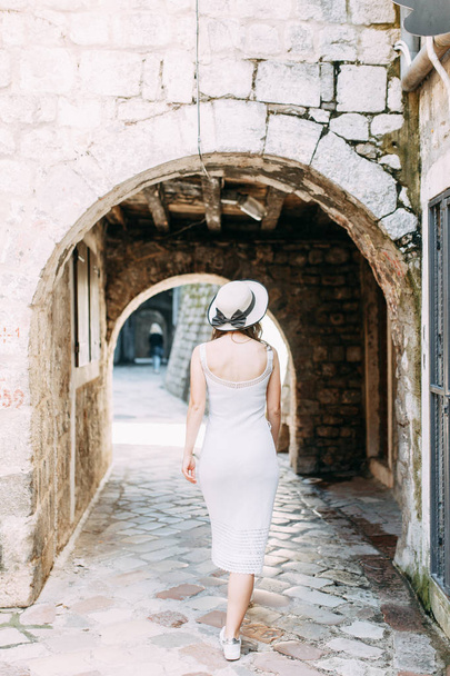 Fotografia de verão nas ruas de Kotor, Montenegro. Menina bonita em vestido branco e chapéu
.  - Foto, Imagem