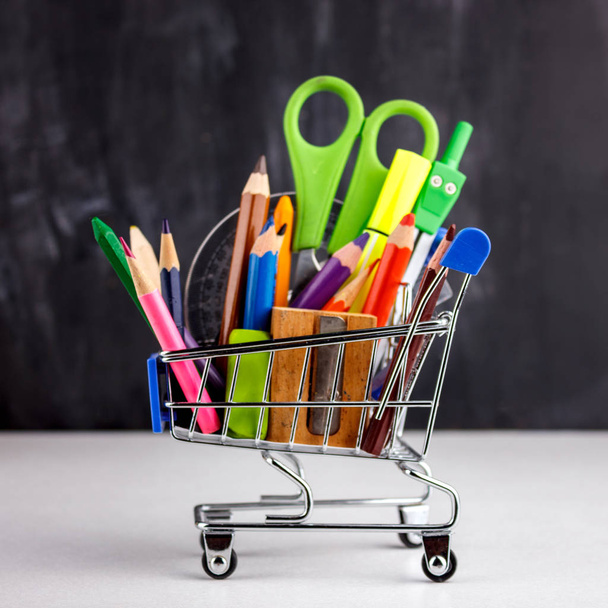 Conjunto de lápis coloridos e marcadores para a escola. Papelaria do estudante - tesoura, afiador, borracha em um carrinho de compras
 - Foto, Imagem