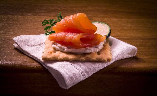 Fetta di salmone su cracker con crema liscia, antipasto su asciugamano bianco
 - Foto, immagini