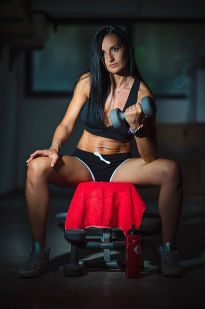 Спортивная женщина с гирями в своем домашнем спортзале в гараже
 - Фото, изображение