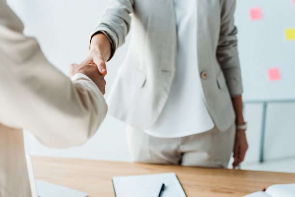 cropped view of recruiter and employee shaking hands while standing  in office  - Photo, Image
