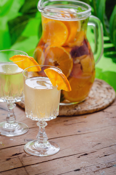 Sklenice bílého šumivého vína, ozdobená citrusovými plátky a sezonní plody na dřevěném stole. - Fotografie, Obrázek